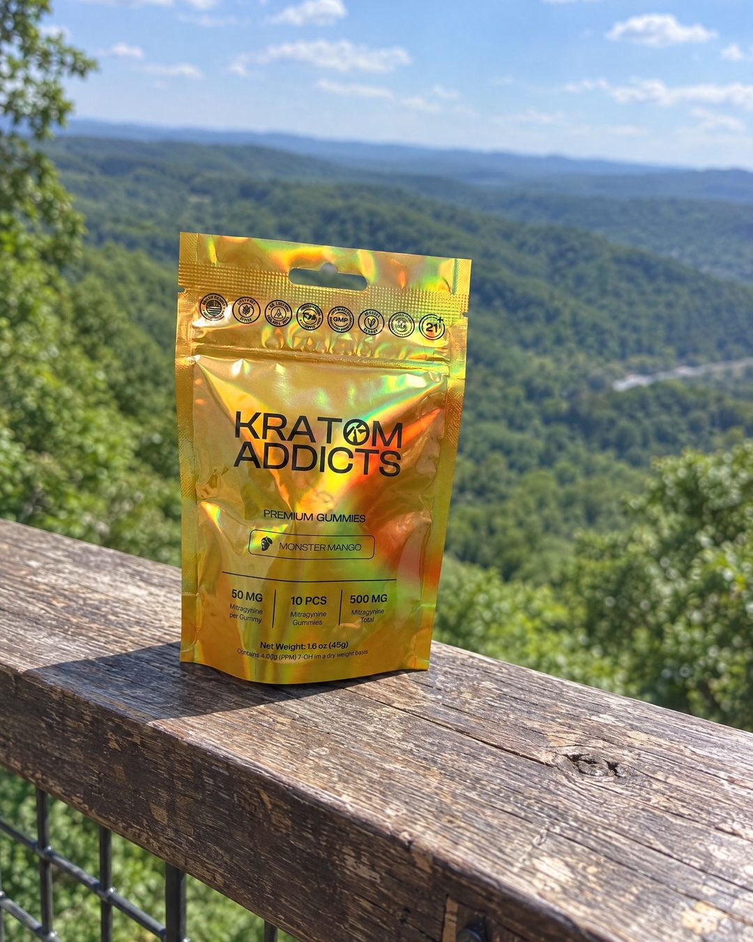 Monster Mango kratom gummies on a deck railing above a wooded valley