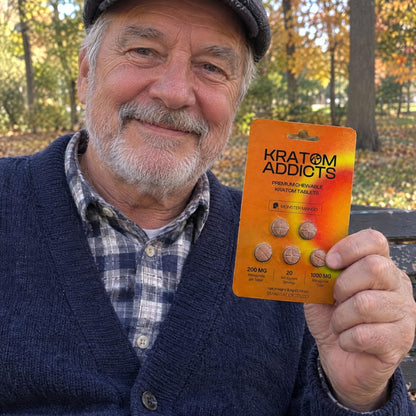 An older man in autumn holding Monster Mango kratom tablets