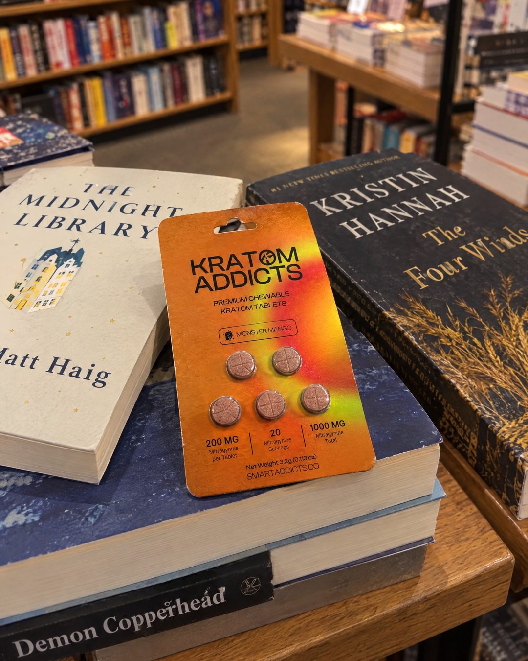 Monster Mango kratom tablets on a stack of books in a bookstore