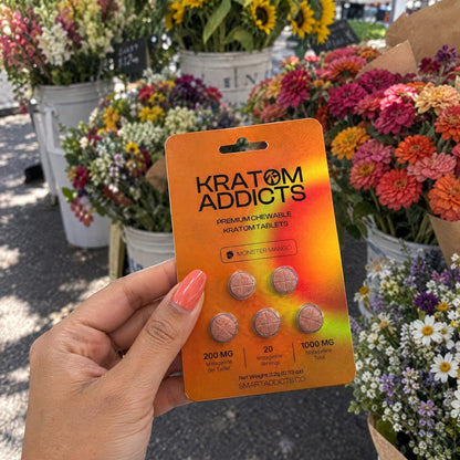 A hand holding Monster Mango kratom tablets at a flower market