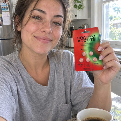 A woman at her kitchen table holding Strawberry Dream kratom tablets