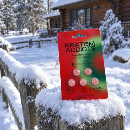 Strawberry Dream kratom tablets on a snowy post outside a cabin