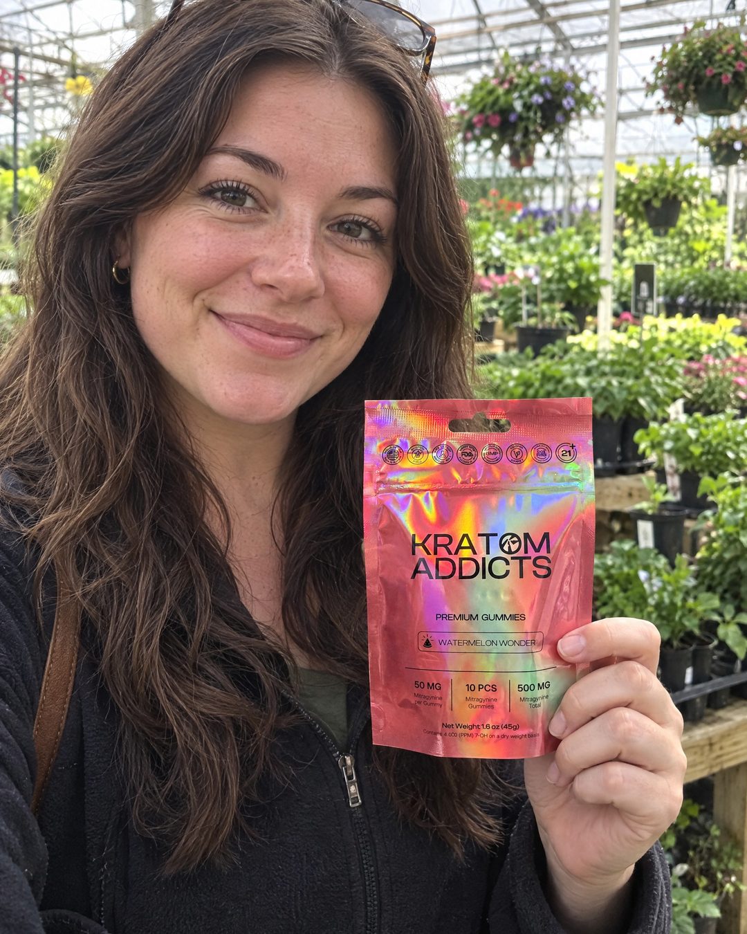 A woman in a greenhouse holding Watermelon Wonder kratom gummies