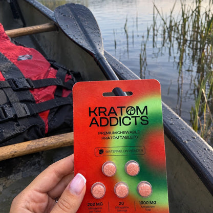 A hand holding Watermelon Wonder kratom tablets in a canoe on a lake