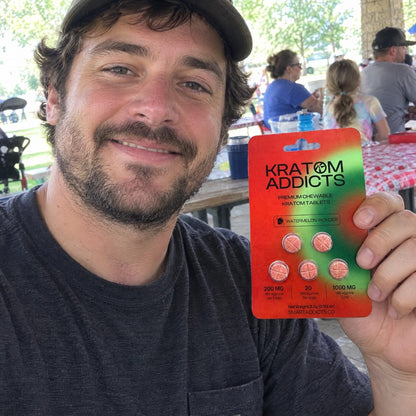 A man at an outdoor table holding Watermelon Wonder kratom tablets