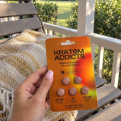 A hand holding Monster Mango kratom tablets on a porch swing