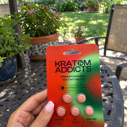 A hand holding Watermelon Wonder kratom tablets on a garden patio